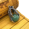 Close-up of vintage silver dragon claw pendant holding a green stone on bamboo mat - Green (Aventurine)