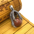 Close-up of a silver dragon claw pendant holding a round red goldstone gem for DIY jewelry - Gold Sandstone
