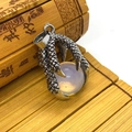 Vintage dragon claw pendant holding a translucent bead on a retro bamboo scroll - Opal