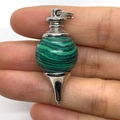 Spherical green malachite stone pendant with silver metal caps held in hand - Malachite