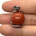 Polished red jasper sphere pendant with silver bail connector held by hand - Rainbow Stone / 16x23mm
