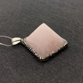Macro detail of pyramid-shaped rose quartz pendant with crystal-encrusted silver base - Rose Quartz