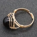 Handmade wire wrapped ring featuring a large polished black stone bead in a gold finish - Black Agate
