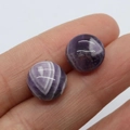 Macro shot of natural purple amethyst cabochon stones held on fingers showing size - Purple Crystal