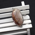 Detail of handmade wire-wrapped natural agate stone pendant with intricate silver wire work - Pink