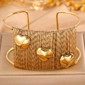 Bracelet jonc tissé en acier titane avec trois accents de cœur dorés sur une boîte à bijoux - Style de Fil d'Acier Tissé