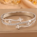 Vue macro détaillée du bracelet trèfle argenté orné de strass blancs étincelants et polis - Acier Trèfle Style