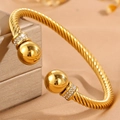 Détail du bracelet doré torsadé avec des sphères serties de strass étincelants - Jonc torsadé doré (Boule dorée)