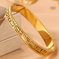 Close-up of golden stainless steel cuff bracelet with Greek key cutout on jewelry box - Gold Line Meander Pattern Bangle
