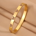 Détail d'un bracelet en acier titane doré avec papillon en cristal rose sur tissu - Papillon Rose