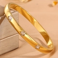Detailaufnahme eines goldfarbenen Stern-Armreifs mit Kristallen auf Schmuckbox - Gold Stern Weißer Zirkonia