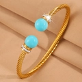 Détail d'un jonc torsadé doré avec perles turquoise bleues et pavage de cristaux brillants - Or Perle Bleue