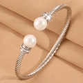 Gros plan d'un bracelet torsadé argenté avec perles blanches et détails en strass - Perle Argentée