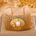 Ethnic style woven gold bracelet with shell detail and pearls on a premium display stand - Open Pearl Style / Gold Steel Wire Shell
