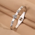 Détail d'un jonc en acier inoxydable argenté avec fleurs de trèfle serties de zircons - Style Trèfle Blanc Argent