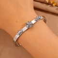 Detail showing an open silver-toned bracelet with crystal inlay on a woman's wrist - Clover Crown (White Zircon)