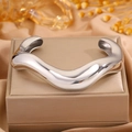 Close-up of glossy irregular wave-shaped stainless steel C-ring bracelet on jewelry box - Steel Wave Open Bangle (Style 4)