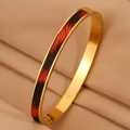 Detalle de pulsera de acero inoxidable dorado con incrustación de patrón rojo y negro - Brazalete Dorado Textura Cuero