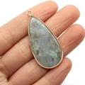 Handgehaltener Labradorit-Anhänger in Tropfenform mit vergoldetem Rand und blauem Glanz - Blitzstein (Labradorit)