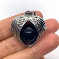 Silver wing-shaped heart pendant with black obsidian bead held by hand for scale - Black Agate
