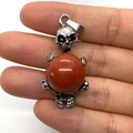 Skull pendant holding a deep red agate bead in silver alloy finish for necklaces - 20x42mm / Rainbow Stone