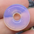 Milchweiß opaliner Donut-Anhänger mit glatter Oberfläche und zentralem Loch im Fokus - Opal