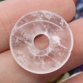Hand hält einen Donut-Anhänger aus klarem Quarz mit natürlicher Eiskristall-Textur - Transparenter Kristall
