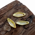 Three natural leaf-shaped shell pendants with carved texture on a rustic wood background - Yellow Shell