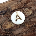 Natural freshwater shell pendant with hollow letter A on rustic wood bark background - Letter A