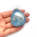 Handheld view showing macro details of the teardrop sea shell resin pendant with pearls - 30x50-40x60mm / Blue