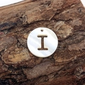 Macro detail of a natural freshwater shell pendant with hollow letter I and iridescent luster - Letter I