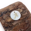 Natural freshwater shell round pendant with golden letter A on a textured wood block - Letter A