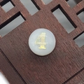 Macro shot of circular white shell bead with gold number four for DIY jewelry - Number 4 / White