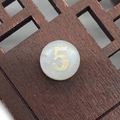 Macro shot of natural shell bead with golden number five on vintage wood background - Number 5 / White
