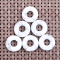 Detail of six howlite doughnut charms with grey marble texture on a woven mat - Howlite