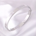Bracelet jonc minimaliste en acier titane poli argenté présenté sur du satin blanc doux - Style Large / Argent