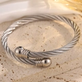 Gros plan d'un bracelet torsadé en acier avec texture de câble et finitions à boules - Argent