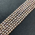 Macro shot of high-luster pale purple oval freshwater pearls arranged on dark grey background - 2-3mm / Pink