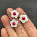 Macro shot of three evil eye shell flower connectors on a finger for size reference - Red