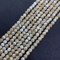Makroaufnahme von polierten Naturmuschelperlen mit creme-weißer Marmorierung für Schmuck - Runde Perle 3mm
