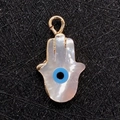 Makroaufnahme von Hamsa-Hand-Muschel-Anhänger mit goldenen Rändern und blauem Auge - 10x17