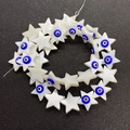 Macro view of star-shaped shell beads featuring blue evil eye charms for DIY jewelry - Blue