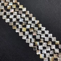 Perles trèfle en nacre naturelle polie avec éclat iridescent sur un fond noir texturé - 12mm / Forme de fleur à quatre pétales