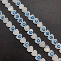 Macro shot of heart-shaped shell beads with evil eye symbols for DIY jewelry making - 13mm / Light Blue