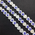 Macro shot of heart-shaped shell beads featuring evil eye detail for jewelry making - 13mm / Blue