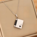 Macro view of a stainless steel envelope locket necklace on a beige jewelry display box - Two-tone Black