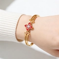 Detail of gold hollowed bangle with red clover motif and sparkling cross diamonds - Red
