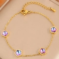 Gros plan d'un bracelet en acier doré avec des breloques fleurs et cristaux violets - Style de fleur multicolore