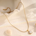 Détail du collier étoile en acier titane doré avec incrustation de perles et de cristaux - Collier Fleur Incrusté de Coquille Blanche