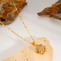 Detailed close-up of golden clover necklace with pink stones and zircons on a stone background - Rotating Pink Diamond Clover Necklace